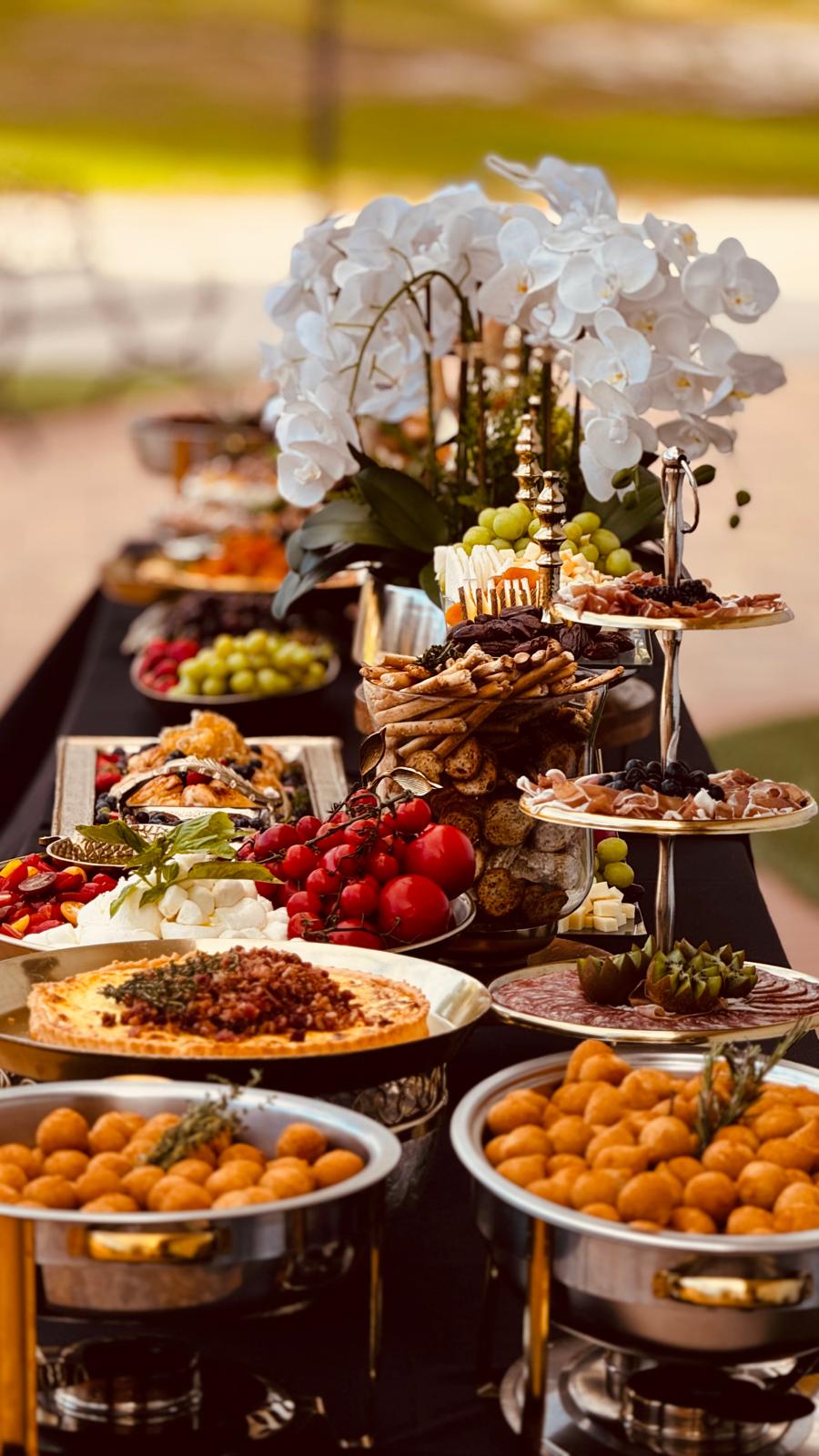 Elegant buffet table with cheeses, fruits, canapés, white flowers and sophisticated décor